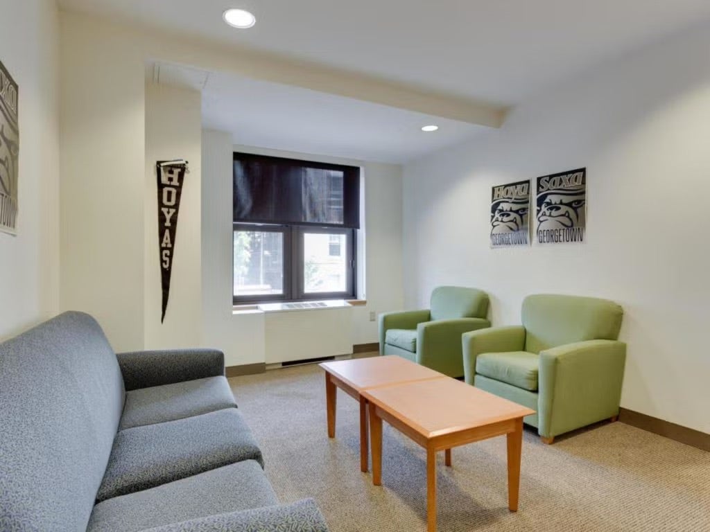 apartment interior with couch and two plush chairs, and a coffee table. There is natural light from the window