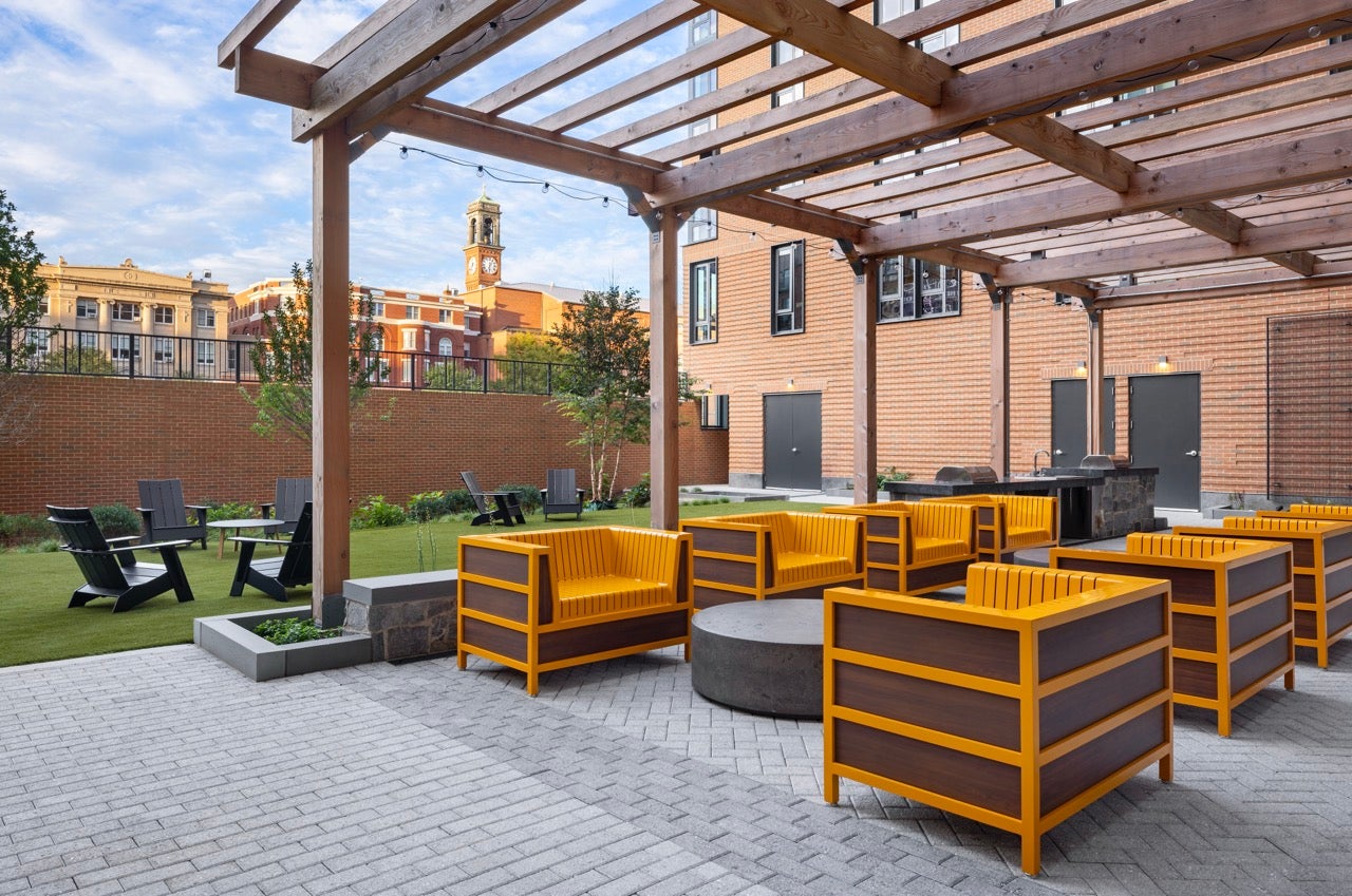 apartment building courtyard with yellow chairs and a wood trellis