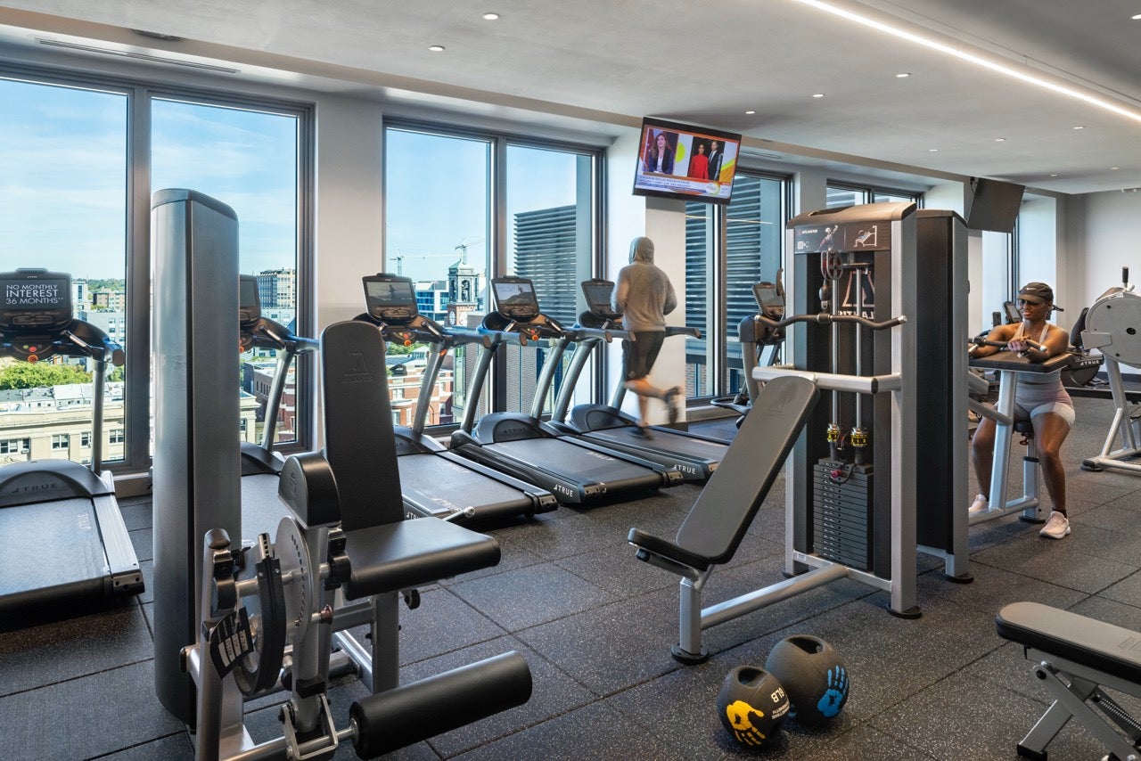 fitness center with cardio and weight equipment and huge windows overlooking a football field