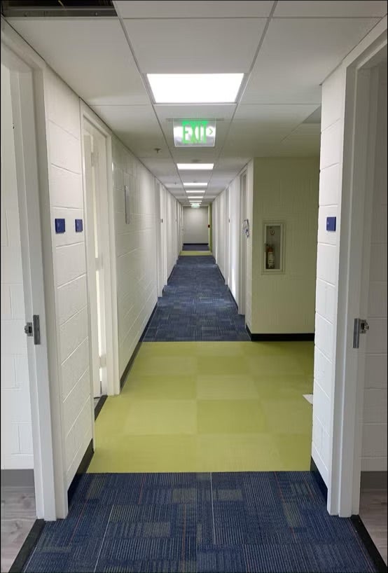corridor with white walls and blue and green carpets