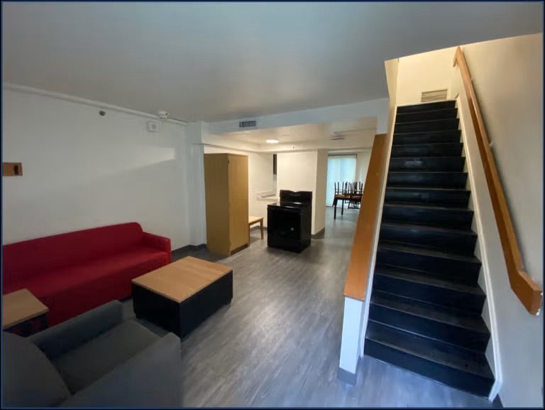 living room with couches and a stairway upstairs
