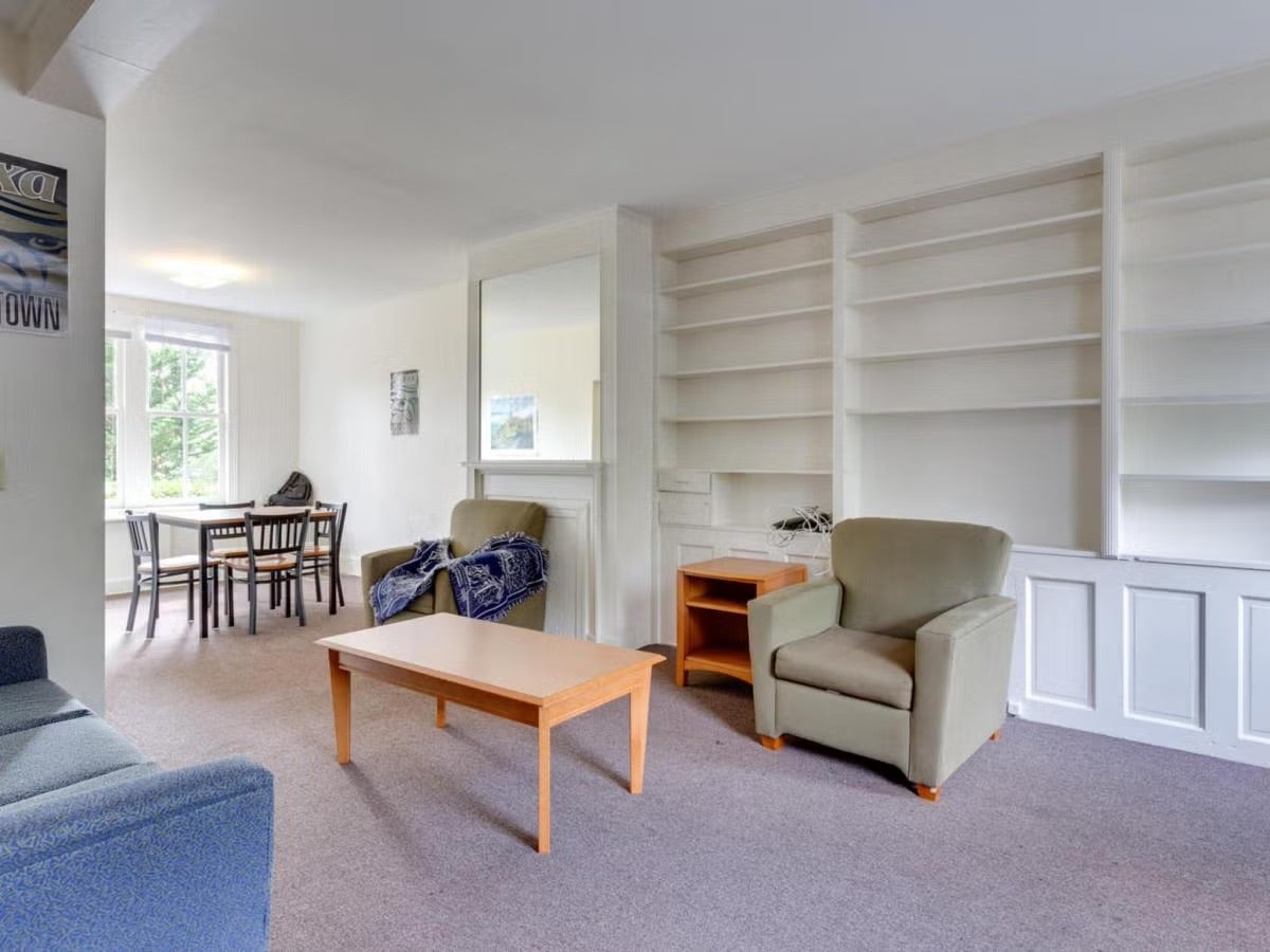 townhouse living room with chairs, coffee table, dining table, and shelves built into the wall