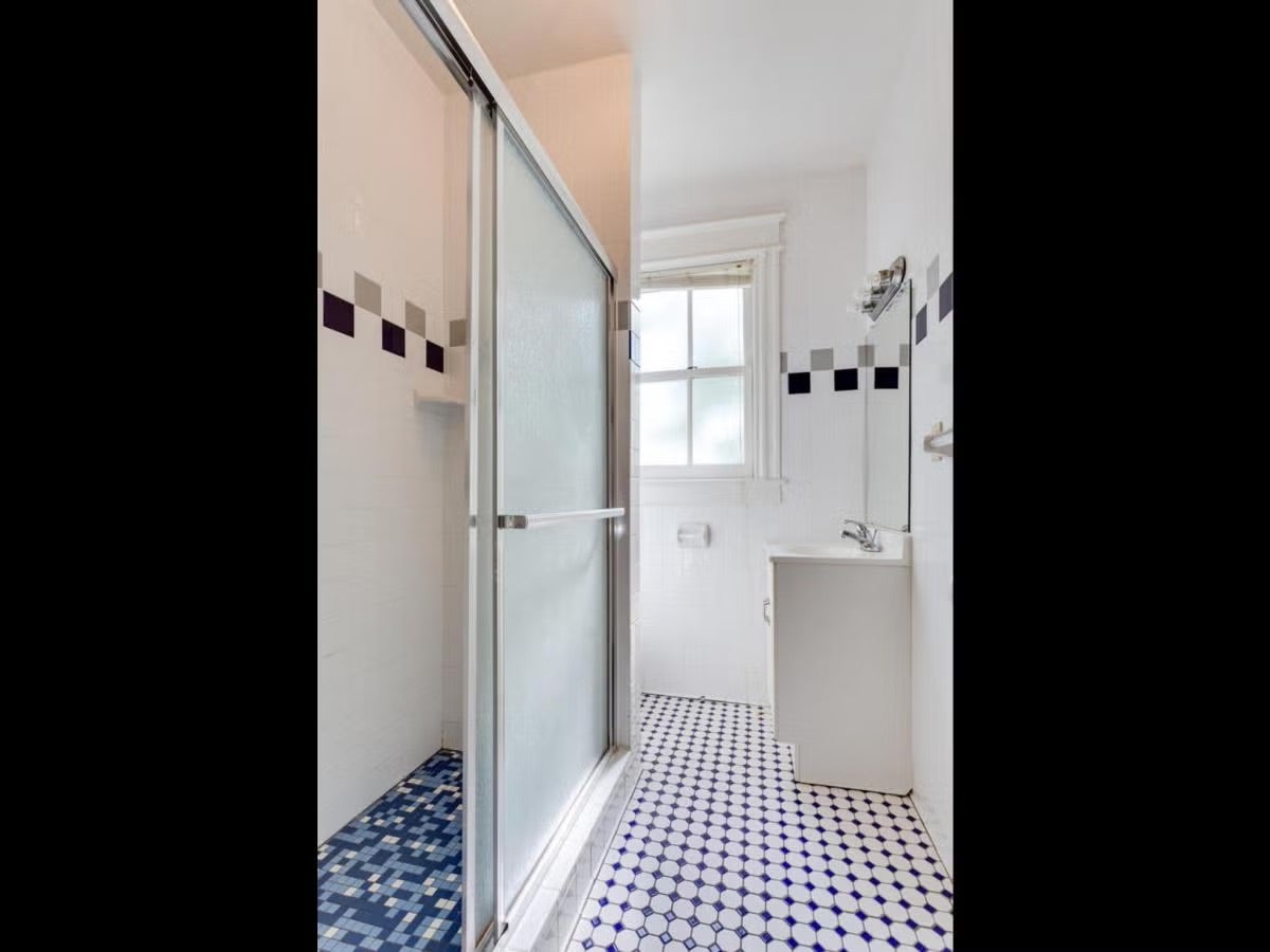 townhouse bathroom with blue tiles on the floor and a standing shower