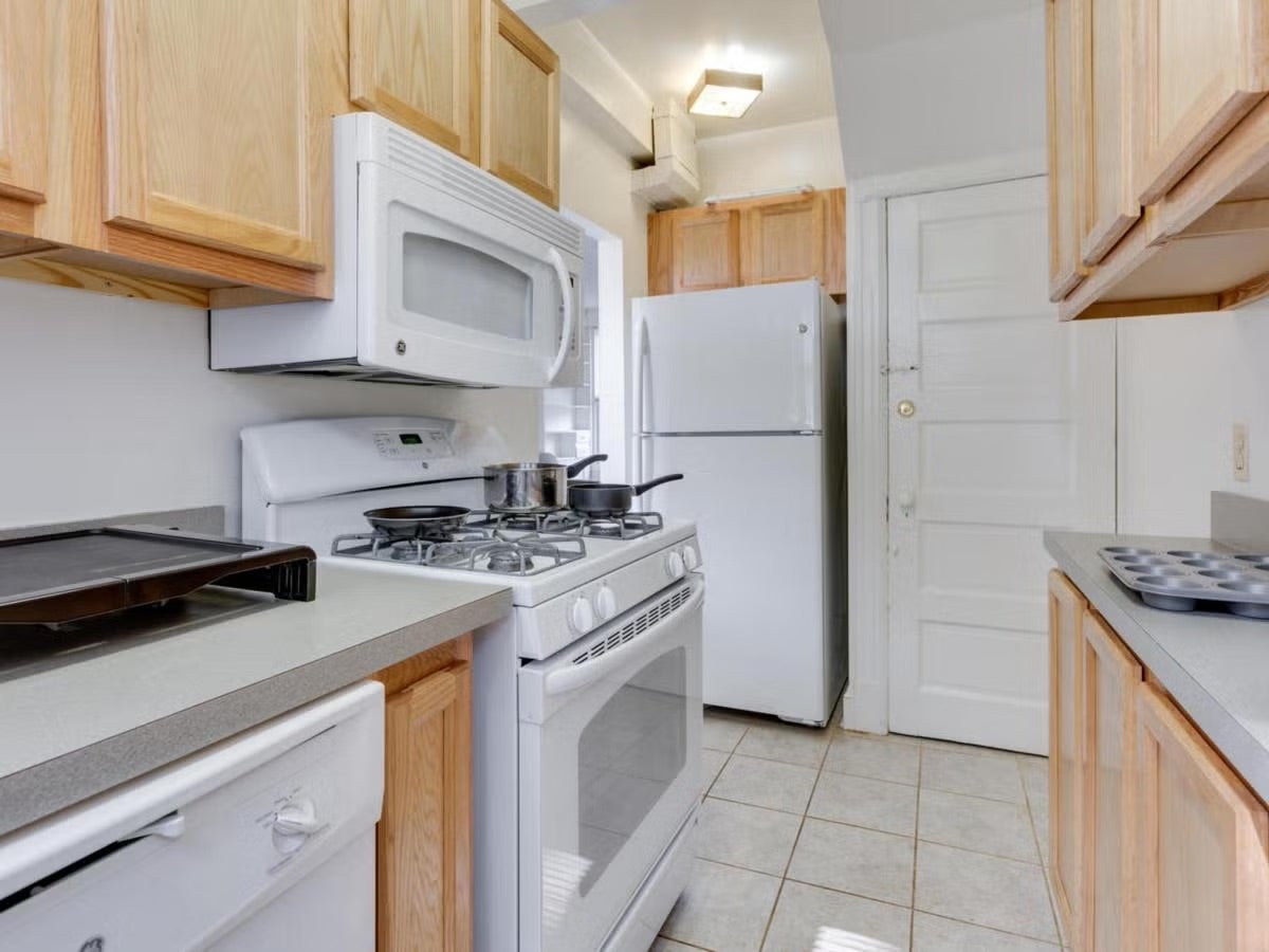townhouse kitchen with wood cabinets and white appliances