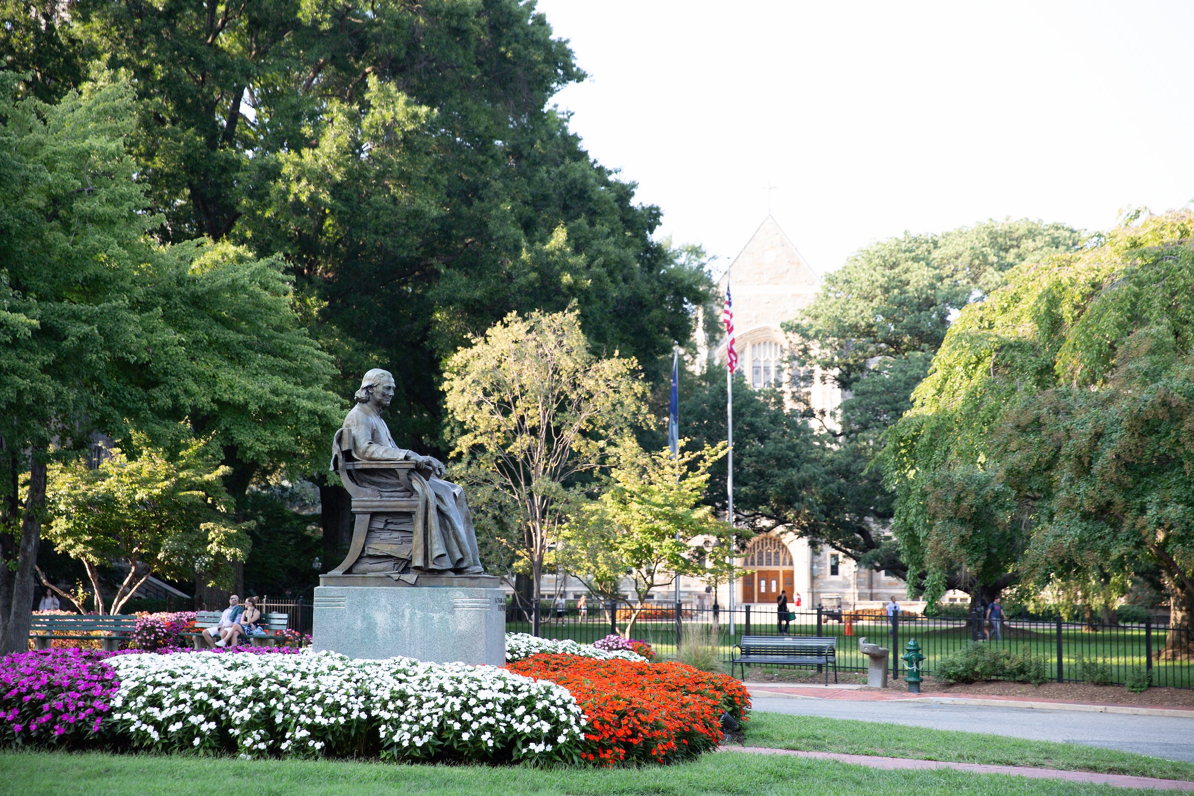 Georgetown's front lawn, showing the statue of John Carroll seated and surrounded by lots of fresh annual flowers