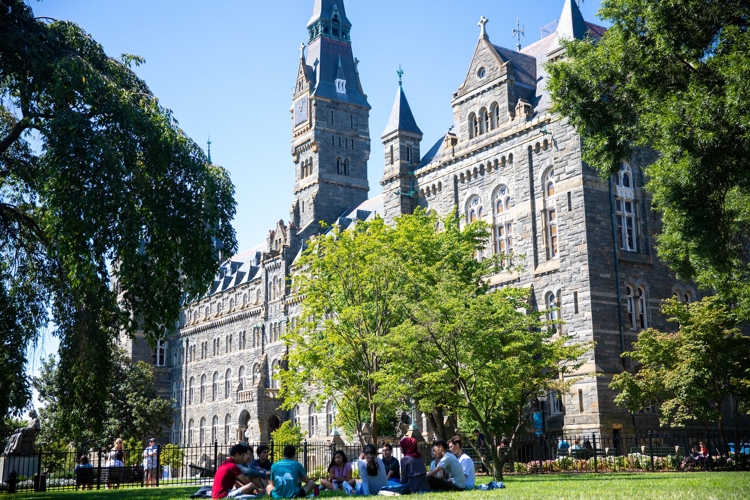 students sitting in a circle in front of Healy Hall