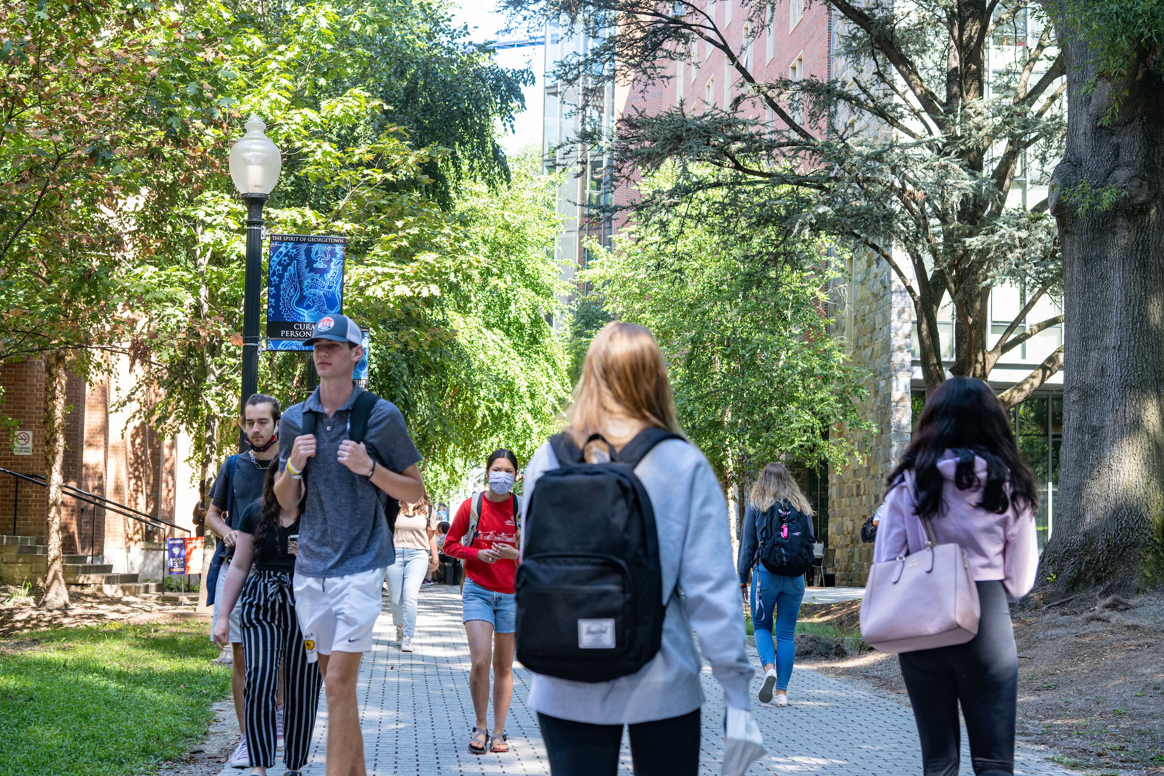 students with backpacks walking to class in an idyllic tree lined area