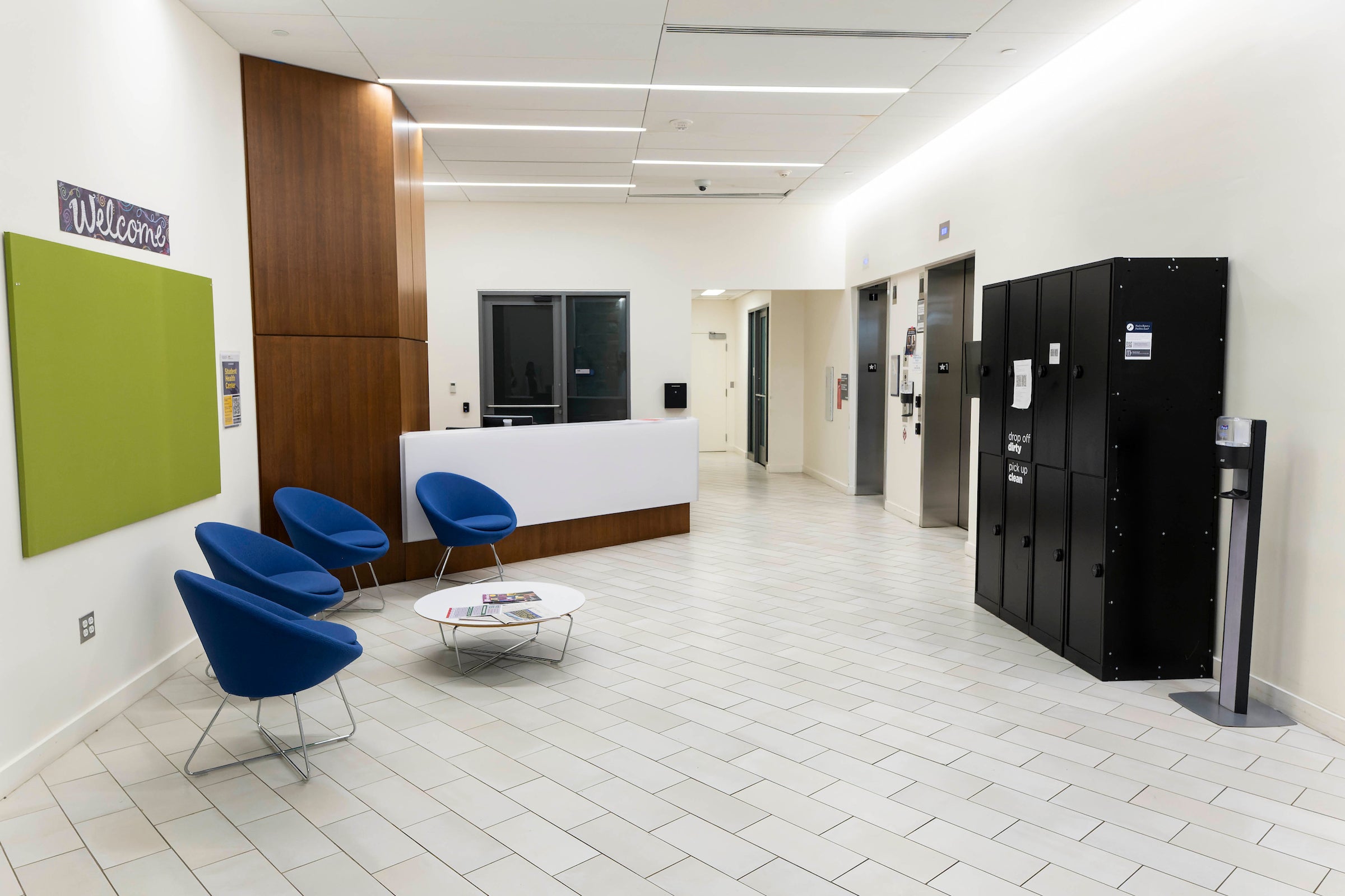 sterile lobby with a front desk, chairs, and elevator bank