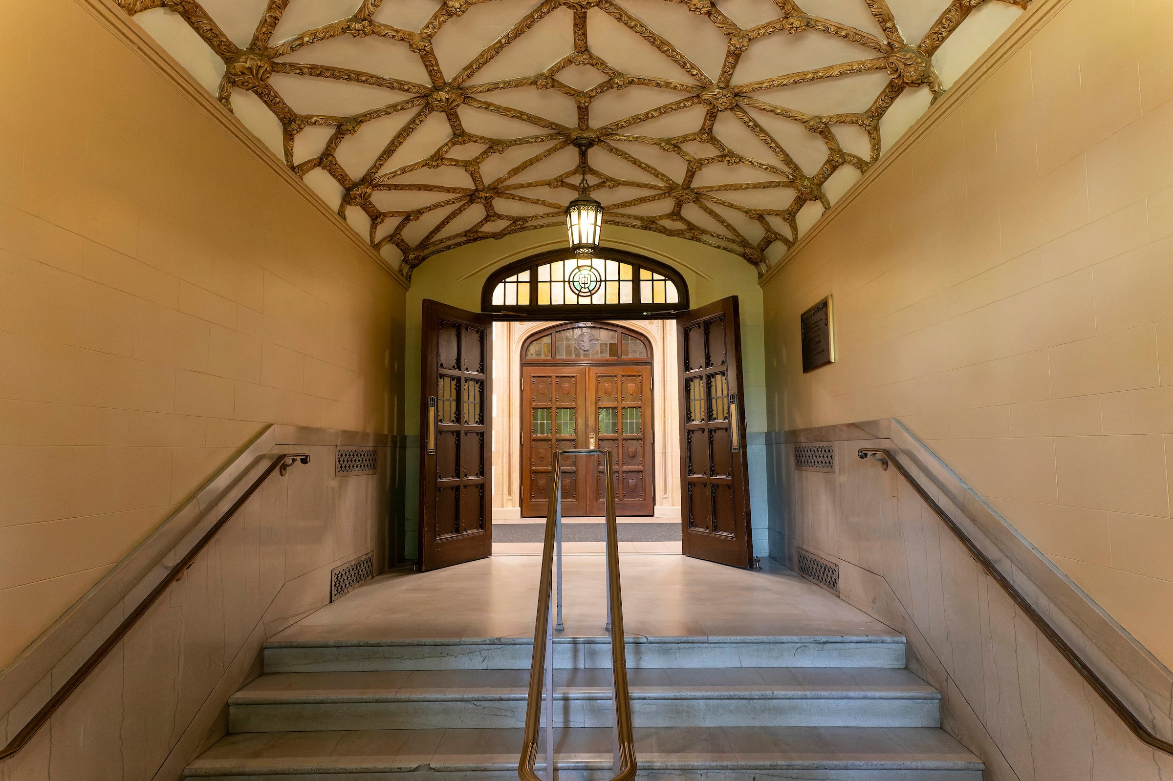 linear perspective of a staircase and hallway with wooden doors and patterned ceiling