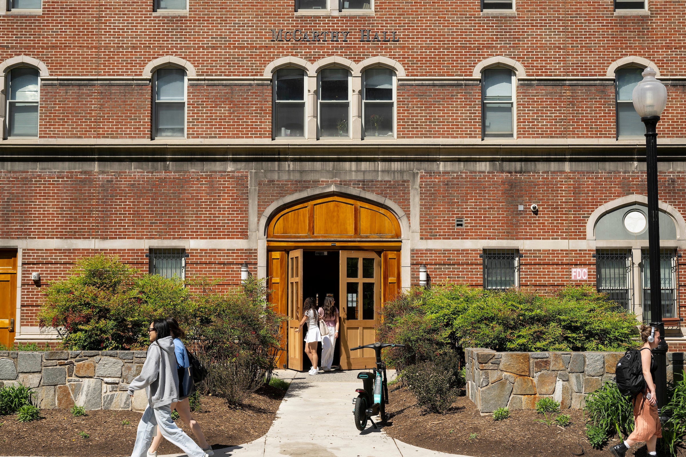 brick building with wooden door and students coming and going