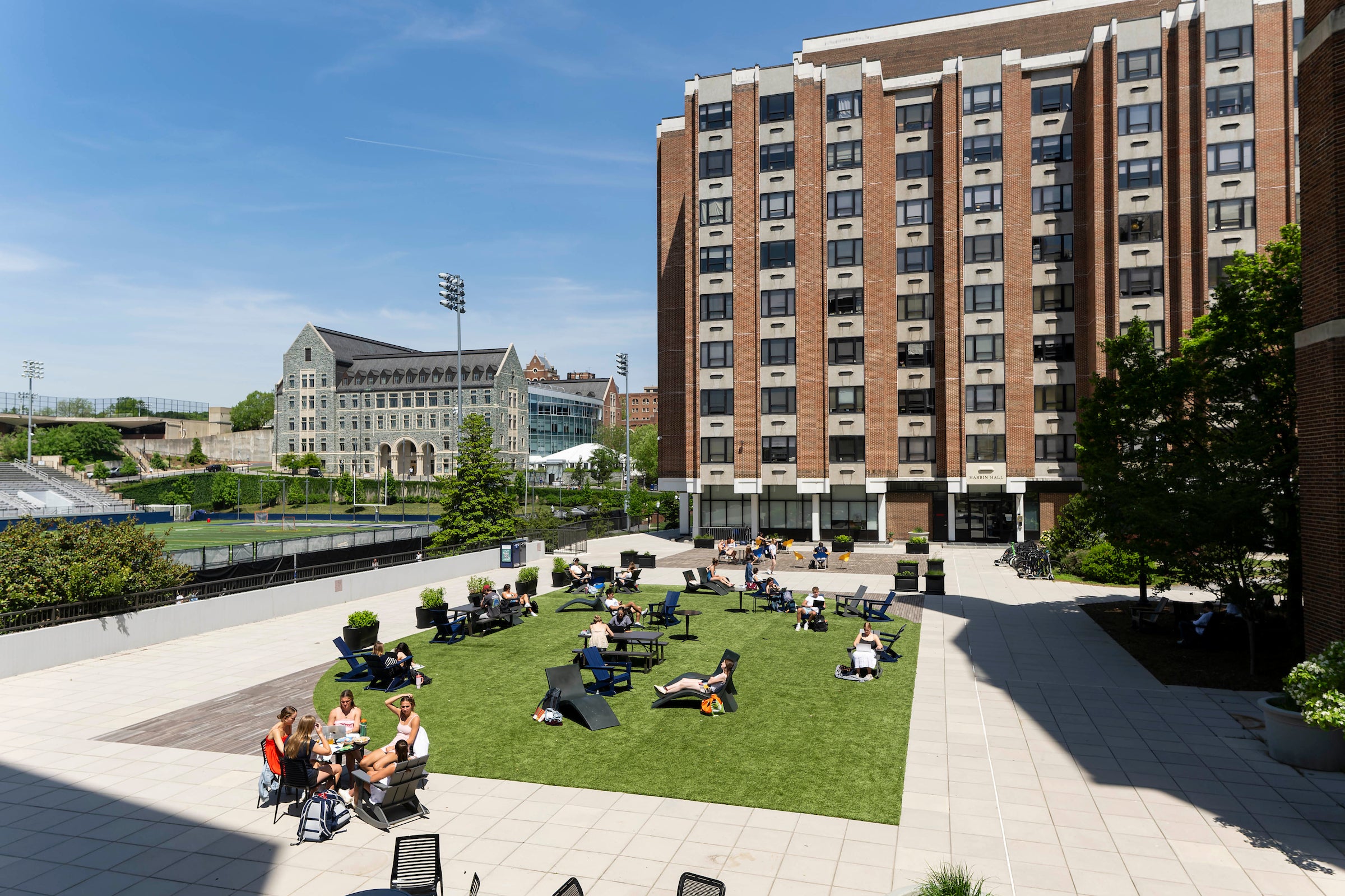 10 story brick building with windows and a large patio with students relaxing in the sun