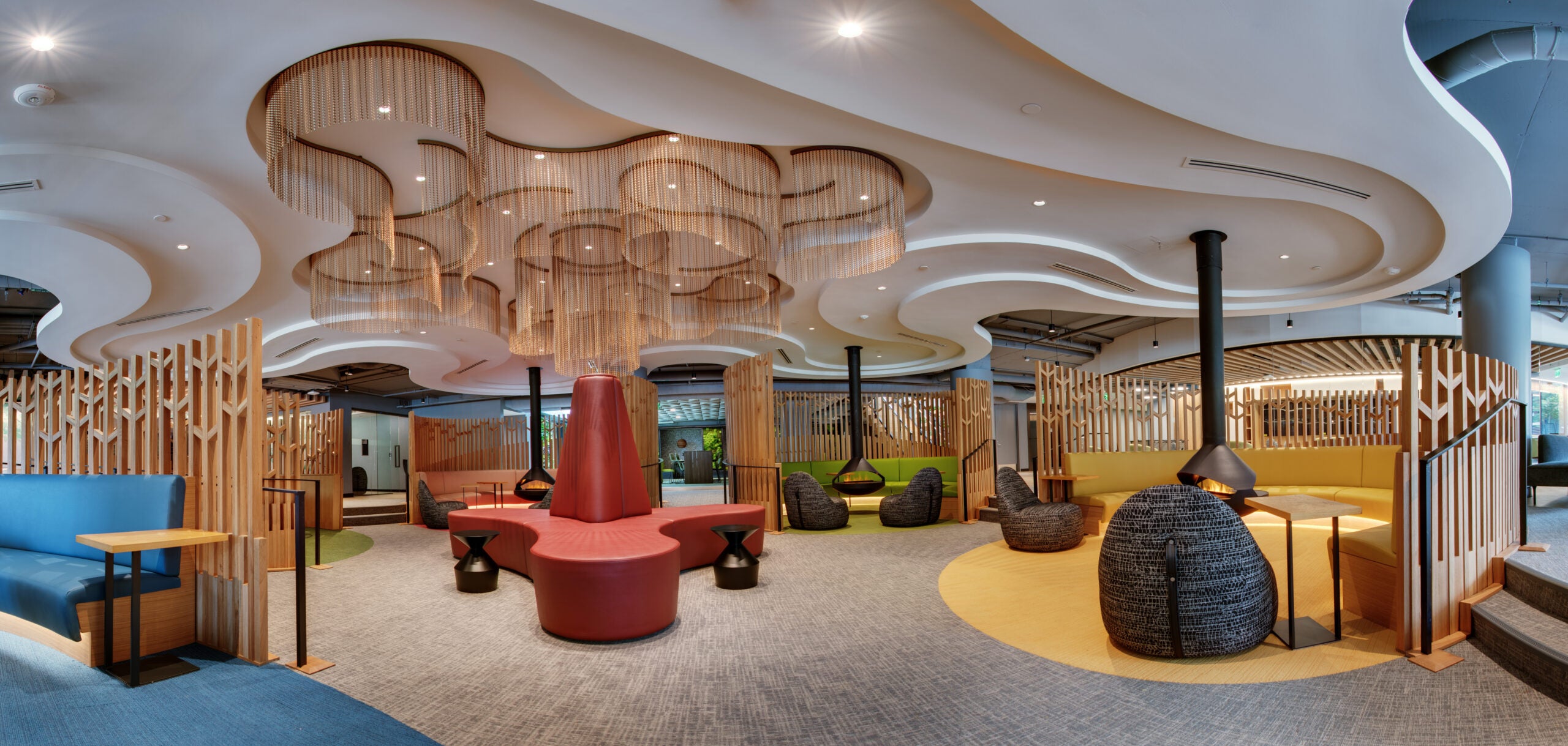 modern conversation pit style lounge with colorful furniture and wavy wooden ceiling art