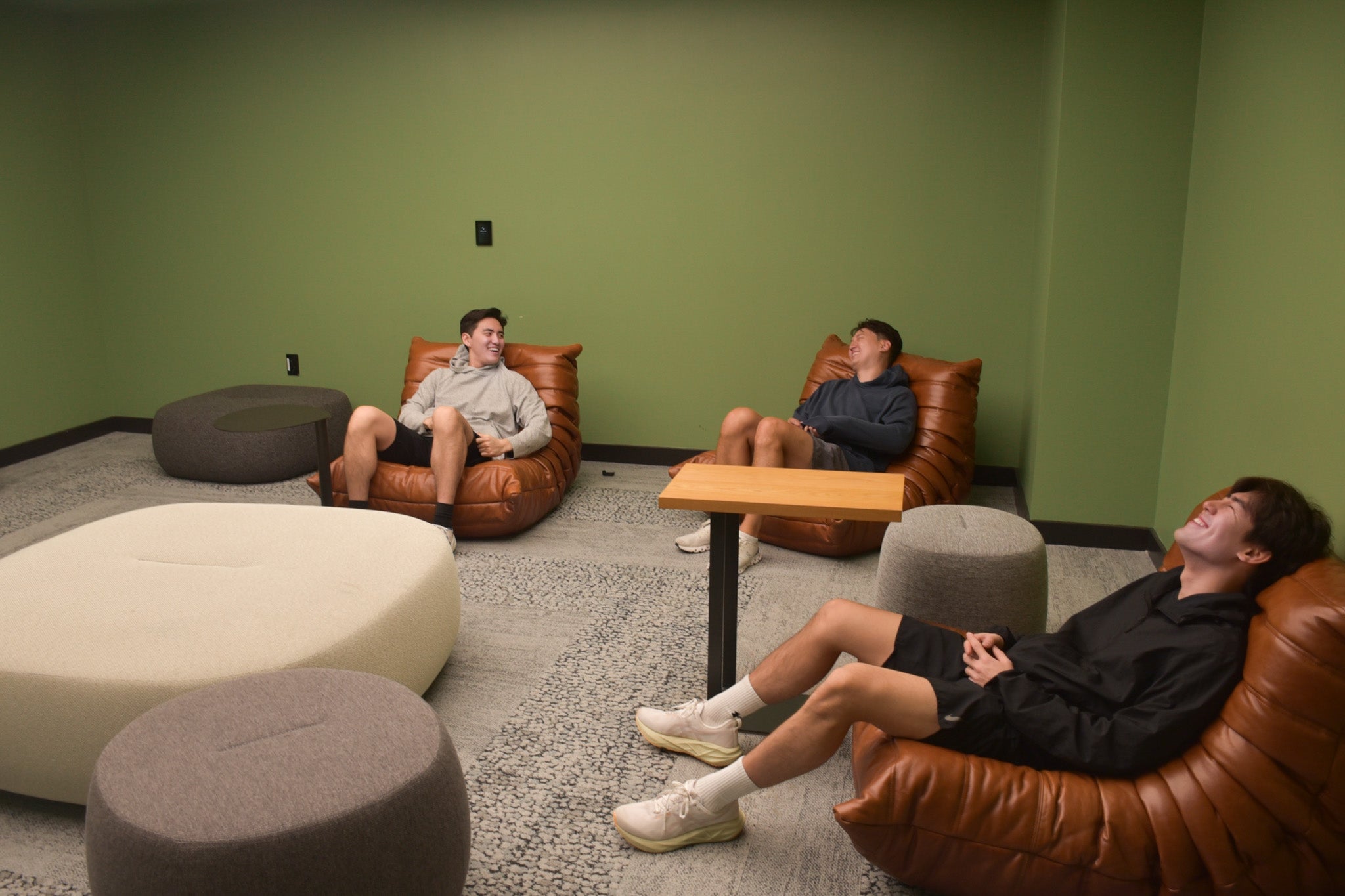 Three students joyfully lounge in an on-campus reflection space.